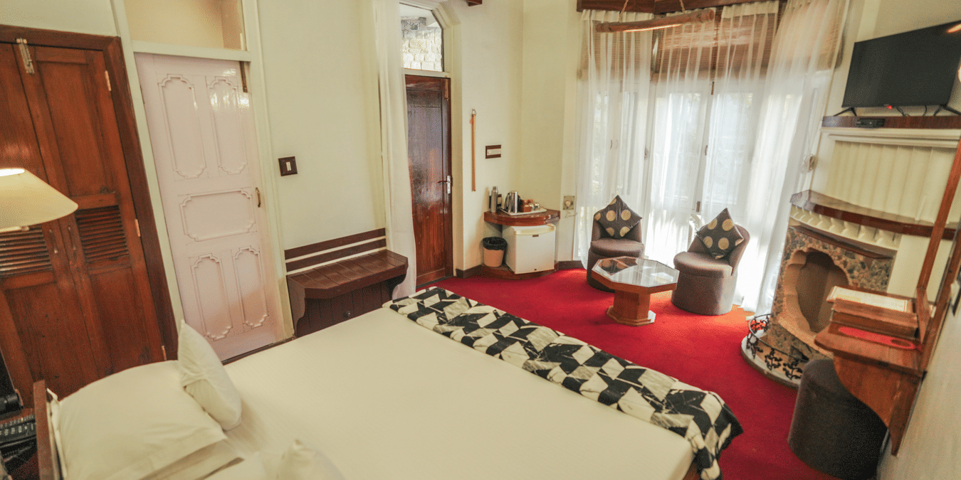 A bedroom with a bed, a rug, and warm lighting, interior setting - The Den Corbett Resort & Spa, Kumeria.
