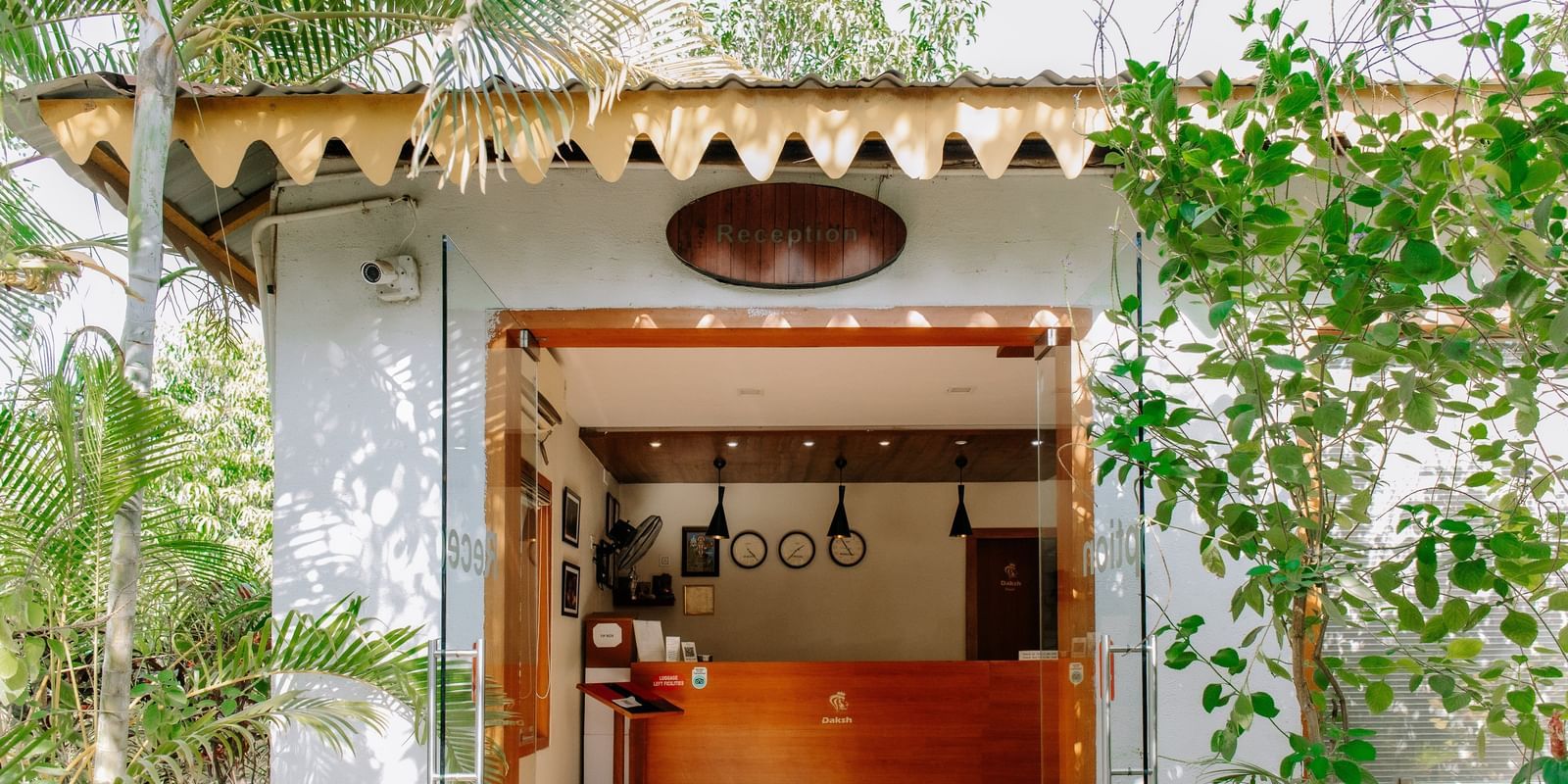 A reception area with a thatched roof, surrounded by green foliage, at Daksh Resort & Amusement Park, Sasan Gir.
