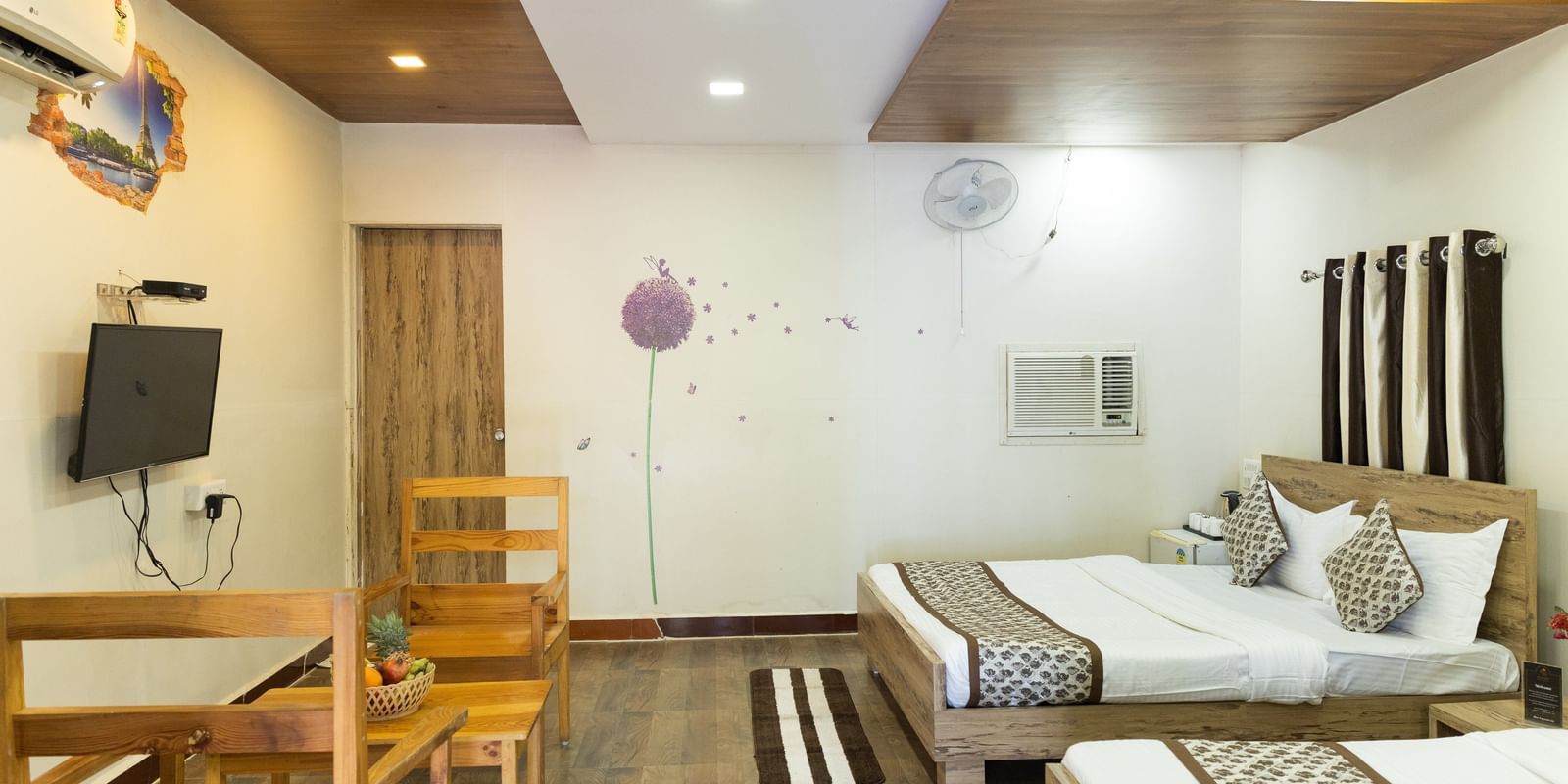 A wide view of a room with 2 beds, a TV, and light wood furniture, at Daksh Resort & Amusement Park, Sasan Gir.