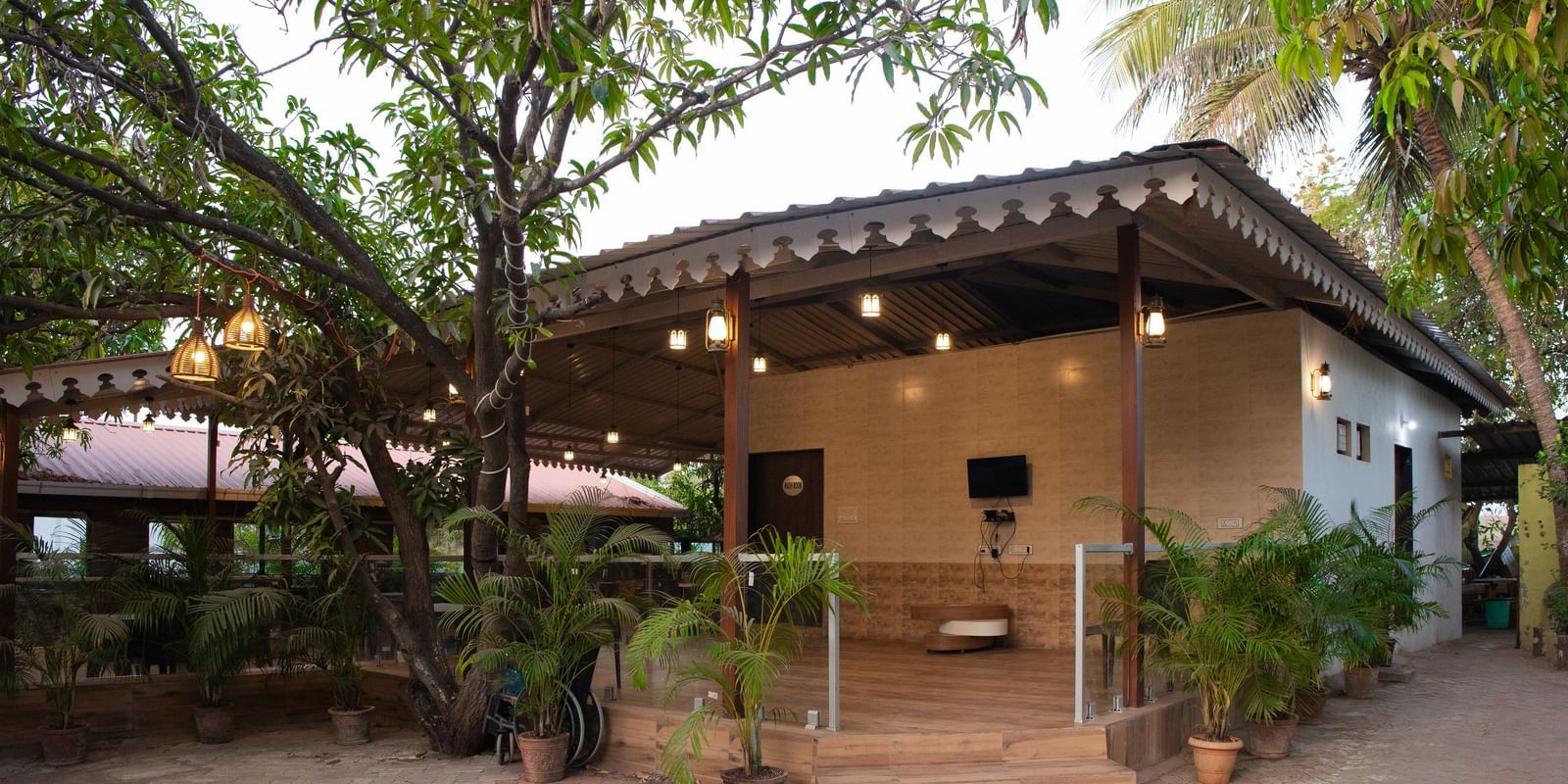 Exterior of Daksh Resort & Amusement Park surrounded by potted plants and trees, with a tiled path leading to the entrance.