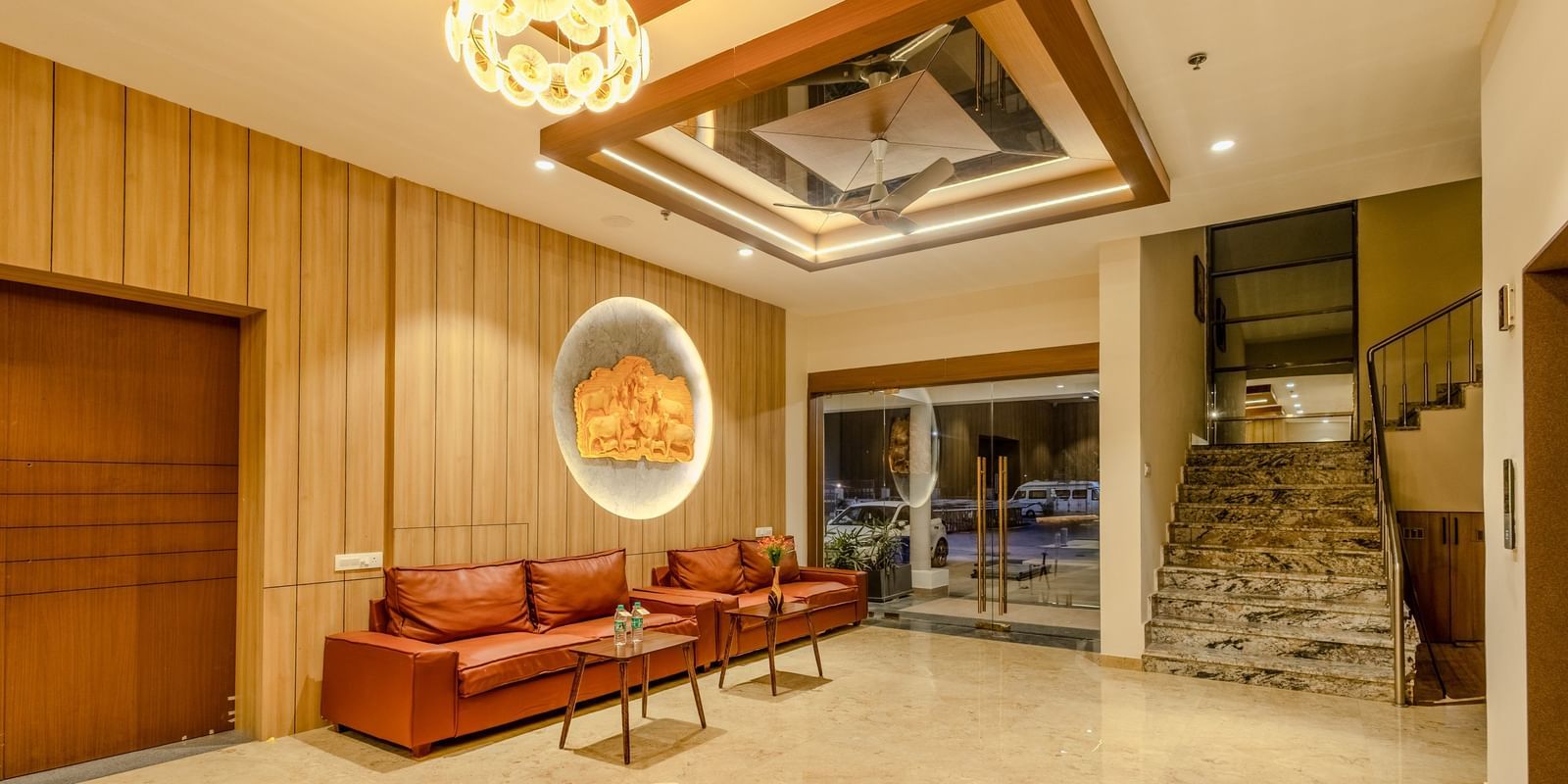 A wide angle shot of an inviting lobby area at Daksh The Grand Gowardhan, Dwarka, with plush seating, elegant decor, and a view of the outside.