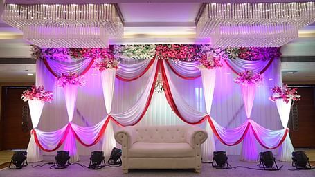 Wedding or event stage decoration with colorful drapes and a white armchair at Rang Lords Inn Bharuch