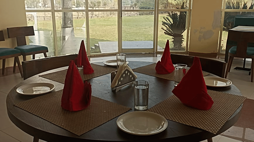 Round dining table set for four with napkins and cutlery at Cafe Treat restaurant at Livbox, Rudrapur.