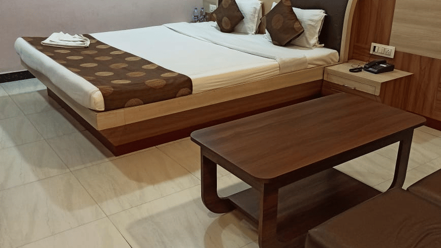 A guest room at Ram Bhawan Ram Yamuna Prasad Hotel & Resort featuring a bright orange accent wall and checkered wood-panel headboard.
