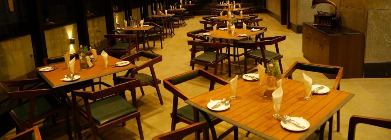 Spacious dining area with tables and chairs set for guests under warm lighting at The Hamuse Hotel, Kodaikanal.