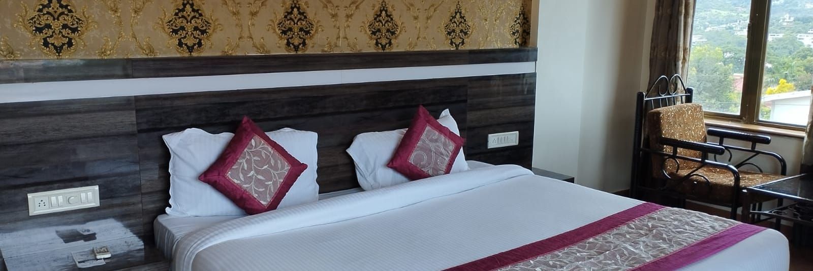 The Super Deluxe Room of Mountview Resort features a king size bed, bedside tables, and a seating area beside the glass windows that offer views of the natural surroundings.