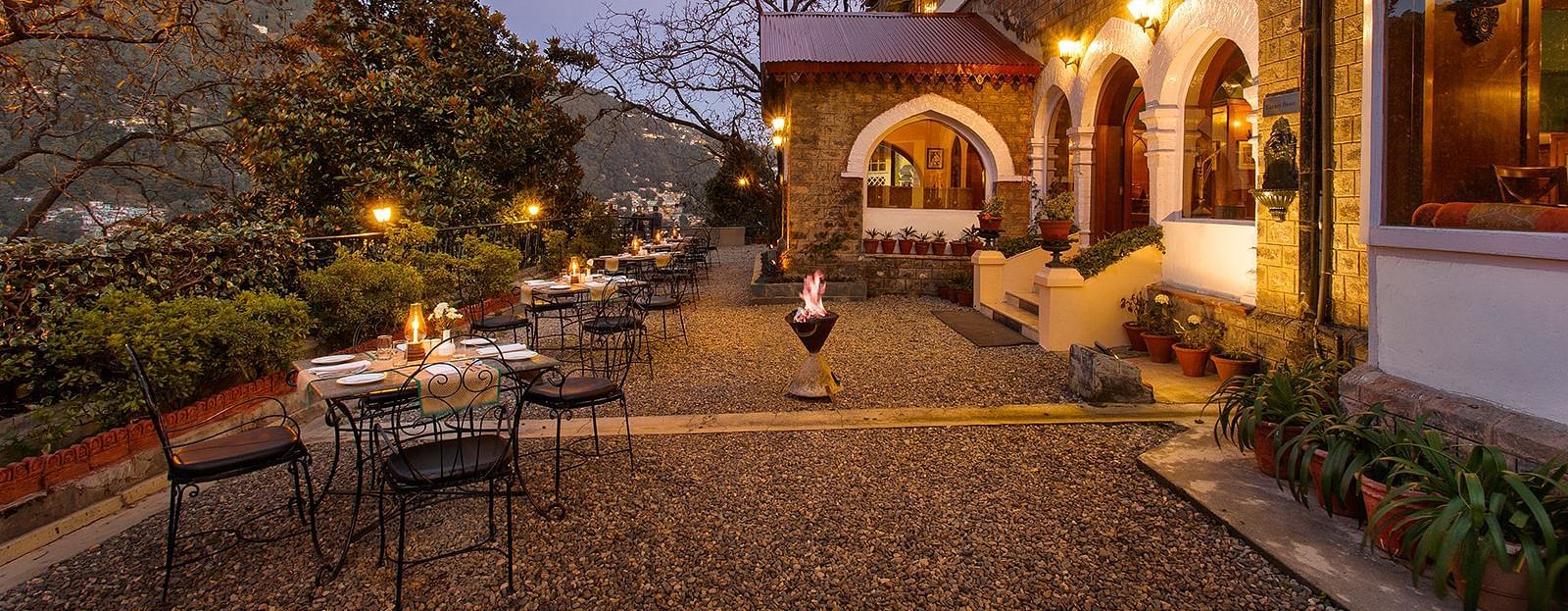 An image of naini retreat, nainital, with a scenic view of  building with a stone exterior and arched doorways. The building is illuminated by warm lights, creating a cozy atmosphere. 