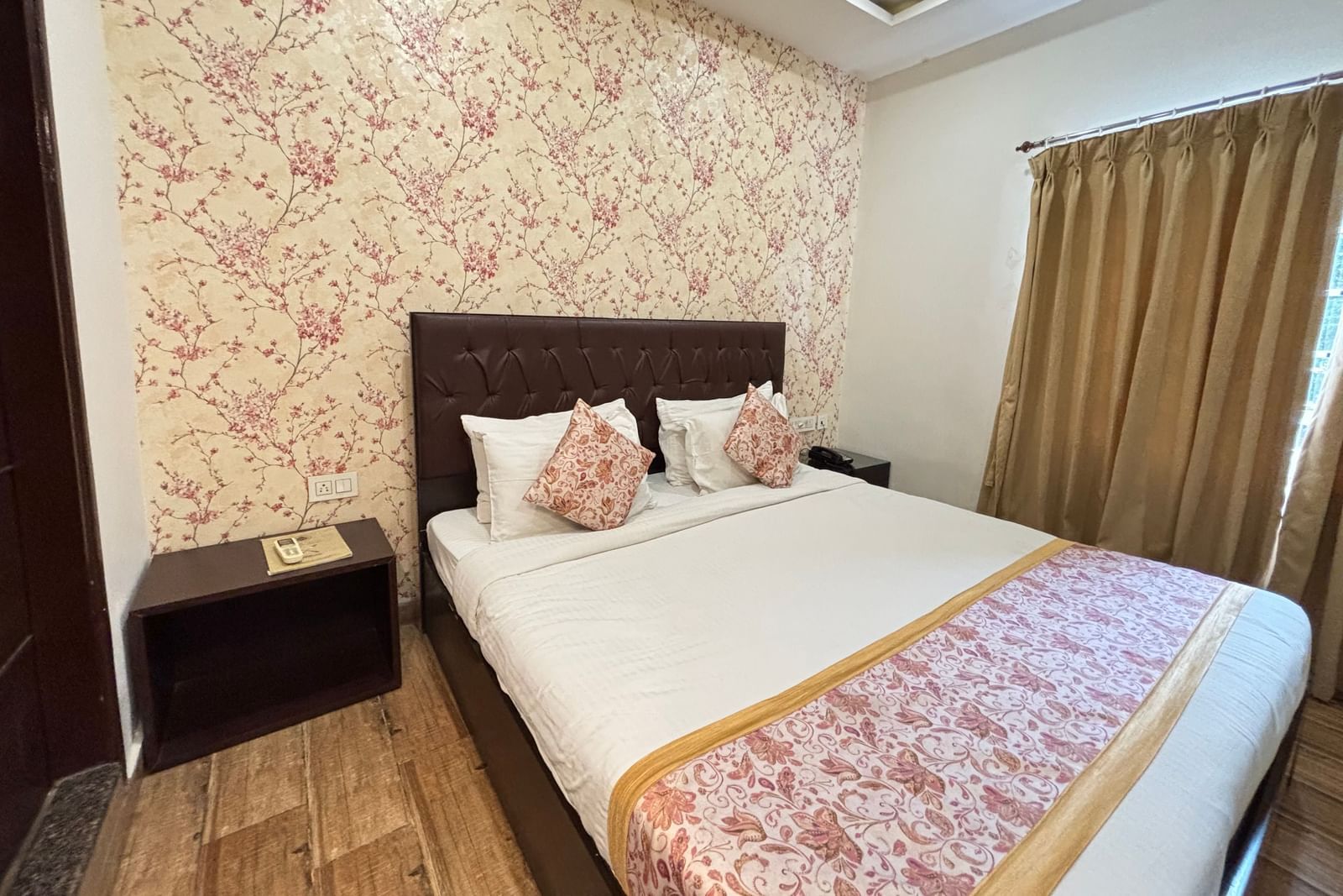 Bedroom featuring a double bed, bedside tables, and patterned wallpaper at Sumitel Premier Inn.