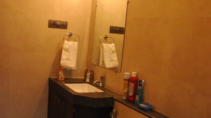 A small, modern bathroom with a toilet, sink, mirror, and beige walls.