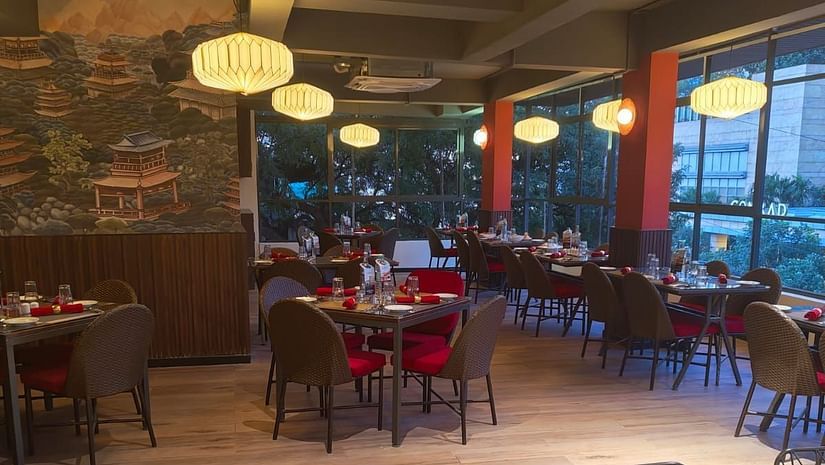 A cosy dining area with tables set for guests, featuring stylish lighting and a comfortable atmosphere for a pleasant meal.