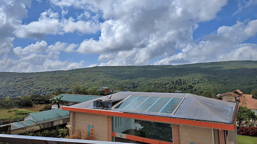 Scenic view of green hills, buildings, and cloudy blue skies