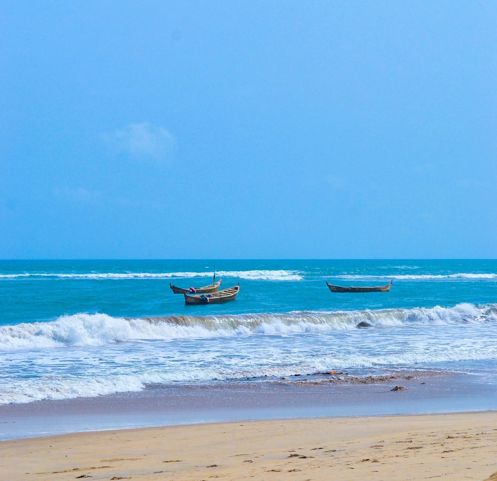 Gentle waves caress a golden sandy shore under the endless blue expanse of the ocean.