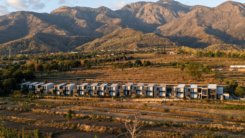 Aerial view of the multiple accommodations at Vandhara Sarovar Premiere, Jim Corbett - Patkote, set against a backdrop of mountains on a sunny day.