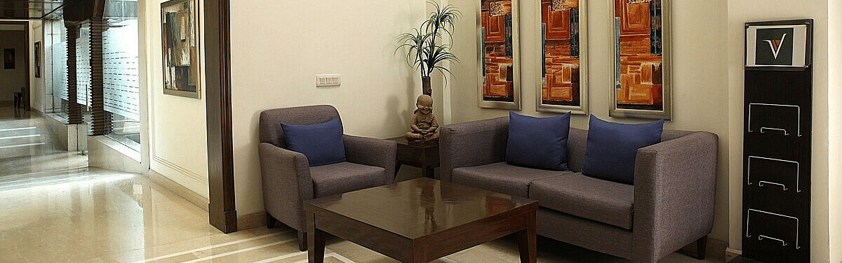 An image of a seating area in a lobby with sofa set and a centre table