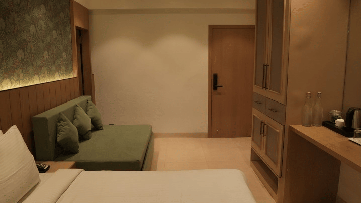 A room featuring a double bed, a sofa, and a wardrobe at Bougainvillea, Alibaug.