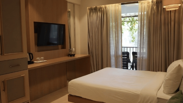 A double bed, a sofa, and a television unit at Bougainvillea, Alibaug.