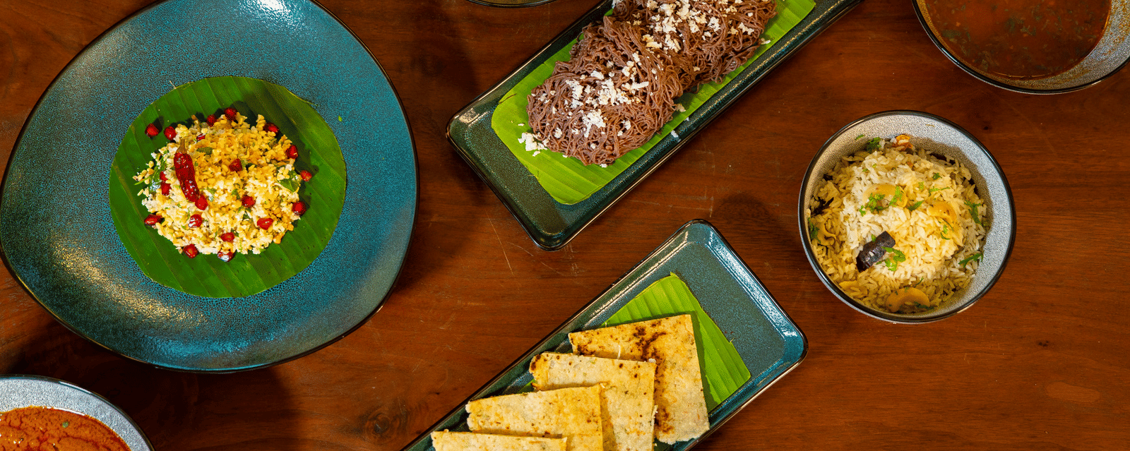 An overhead shot of a dining table at Stanley Revelation, filled with various plates of food on a wooden surface.