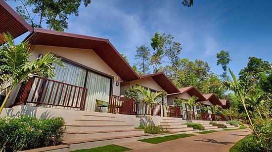 A bright daytime view of the Premium Cottage with a well-maintained pathway and tropical landscaping.