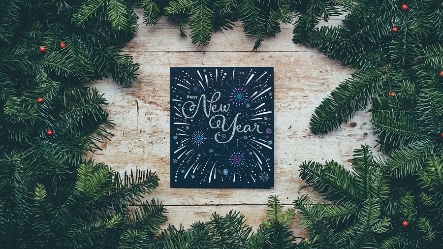 An aerial view of a black board with the words New Year written on it and surrounded by leaves