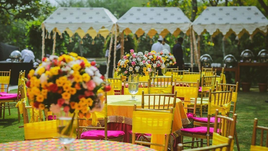 Outdoor wedding reception with yellow chairs, floral centerpieces, and white tents, highlighting a bright, celebratory atmosphere.