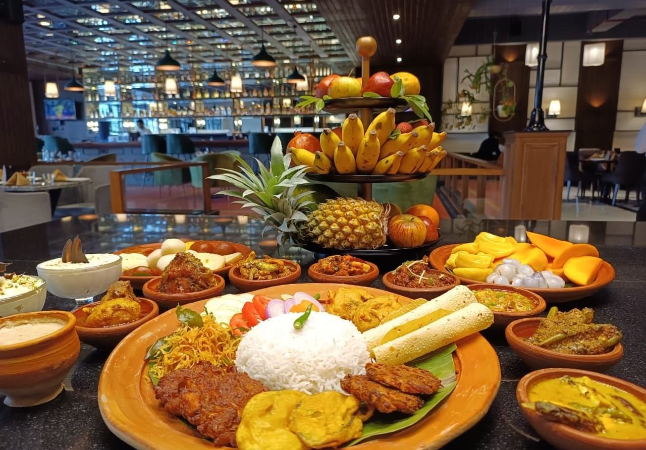A traditional spread of Indian cuisine with fruits, rice, curries, and fried delicacies - Polo Hotel Agartala