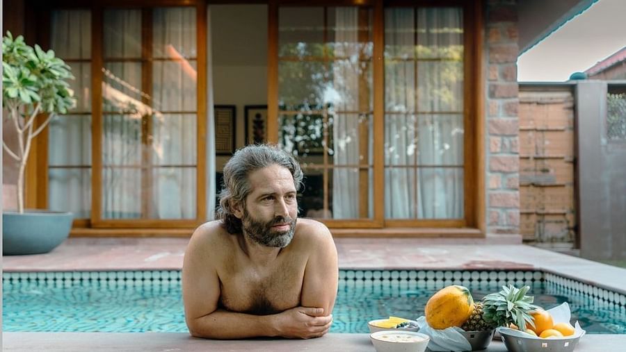 A man standing on a swimming pool with an assortment of fruits on the side at Surpura Bagh.