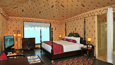 Side view of a room with a bed and a television in front of the bed at Rajasthali Resort & Spa Jaipur.