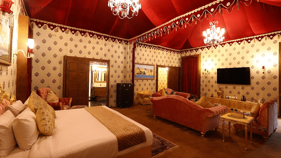 Image of a room with a bed and chandeliers hanging from the ceiling at Rajasthali Resort & Spa Jaipur.