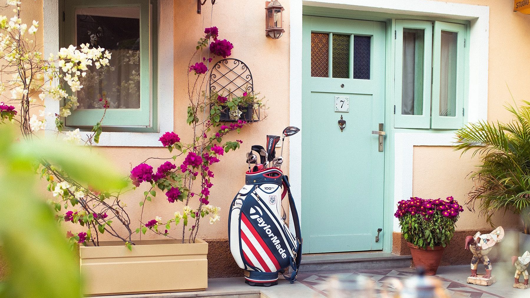 The entrance door to a unit at Karma Chalets with potted plants and a golf bag outside.