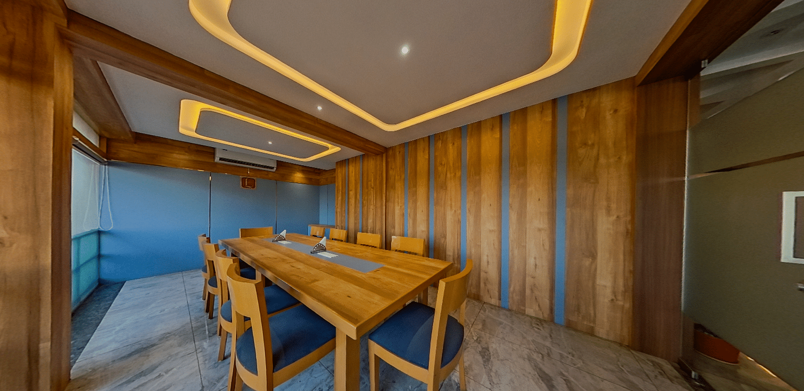 Elegant conference room at Lords Eco Inn Dahej with wooden paneling, blue upholstered chairs, and modern lighting for corporate meetings