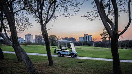 A golf buggy parked on the pathway next to the golf course - Karma Lakelands.