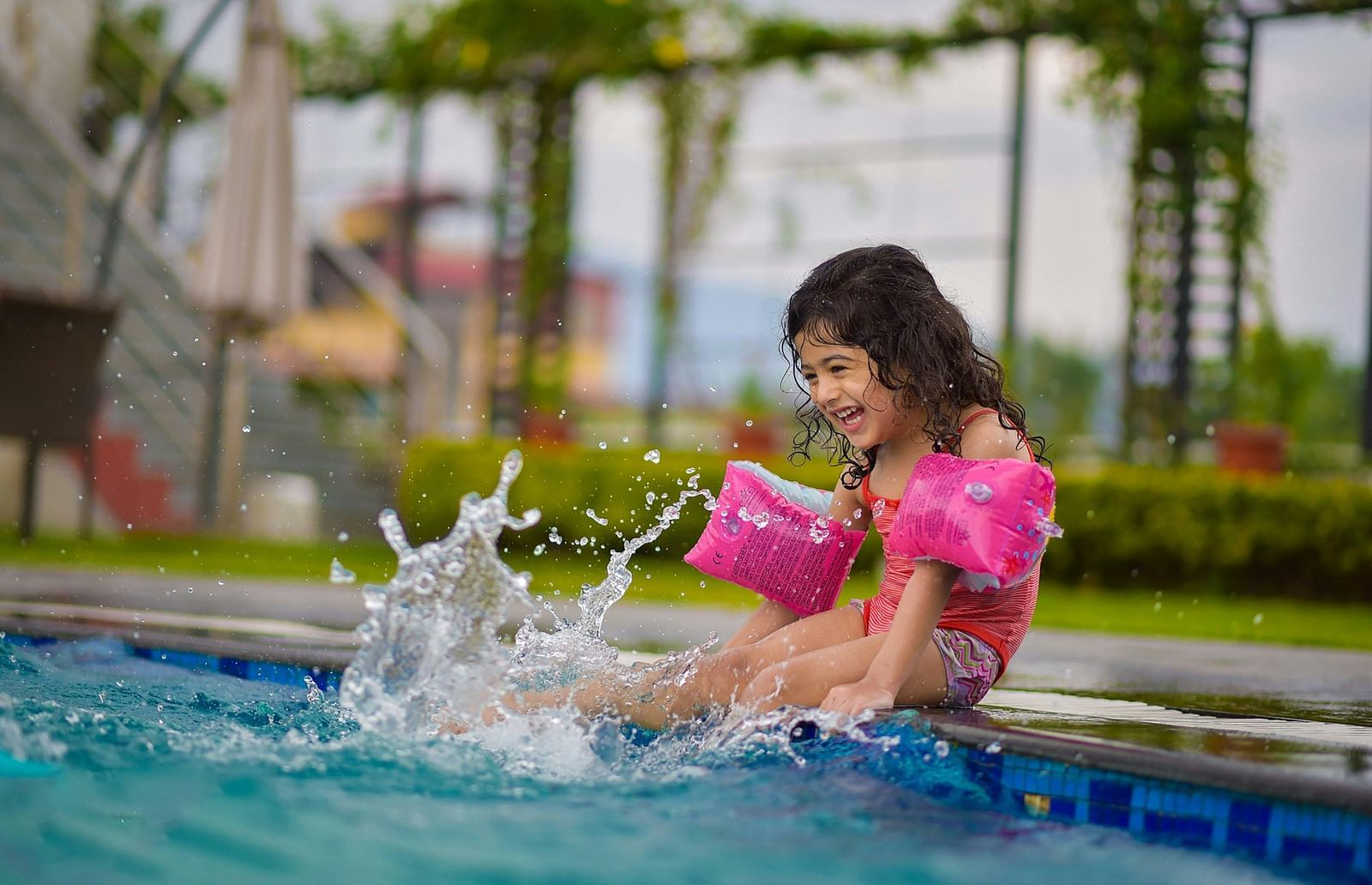 A kid splashing water from the pool.