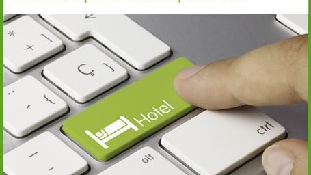 A finger pressing a hotel booking key on a white keyboard.