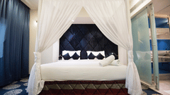 a king bed with pillows and mosquito net on it inside Suite at VITS Sharanam Thane 4