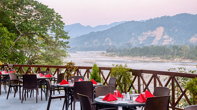 Covered outdoor dining area with tables and chairs and mountain views.