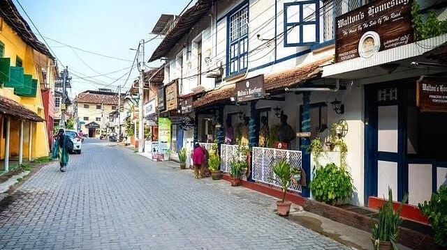 Cobbled street lined with colonial-style houses, balconies, and flower pots in Fort Kochi.