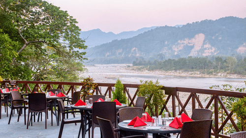 Covered outdoor dining area with tables and chairs and mountain views.