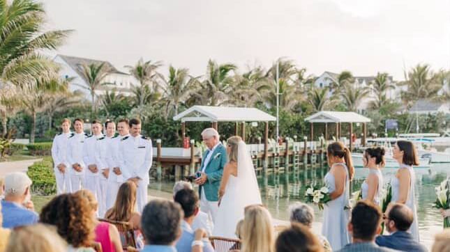 Outdoor wedding ceremony in progress with guests seated facing the couple and officiant, palm trees in the background at Abaco Inn.