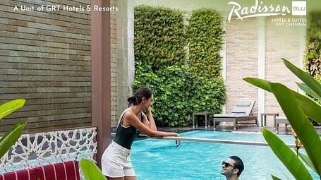 Creative lifestyle photography capturing a couple enjoying leisure time by a private pool surrounded by lush green walls and tropical plants, demonstrating the urban escape weekend offer's relaxing poolside amenities and serene atmosphere.
