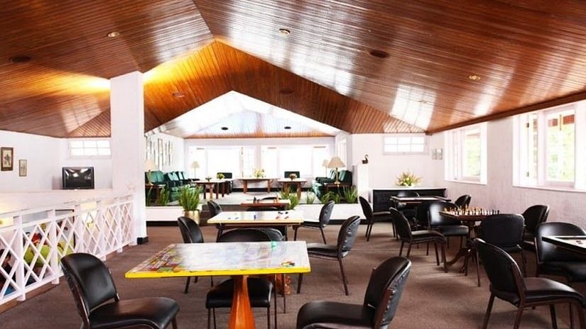  A spacious dining area with a high wooden ceiling, various tables, and black chairs