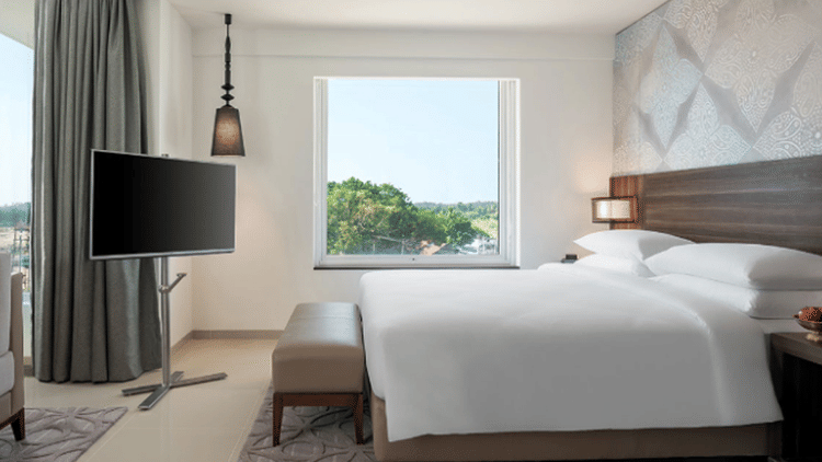 King Room with pool view arrayed with a plush bed and television at The Residency Towers Rameswaram