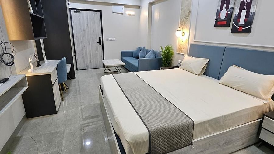 A spacious room with a large bed, side photo frames, and a wall-mounted TV at Urban Suites by BluSalzz, Jaipur.