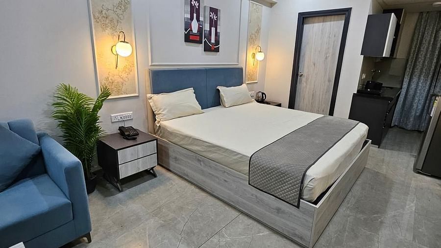 Diagonal view of a spacious room with a large bed, bedside lamps on both sides, and the bedroom at Urban Suites by BluSalzz, Jaipur.