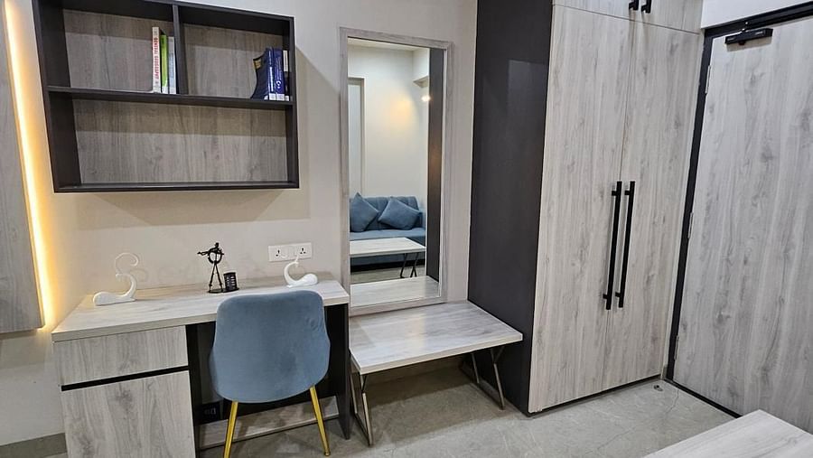 A view of the reading table placed against the wall, with a mirror and a cupboard beside it at Urban Suites by BluSalzz, Jaipur.