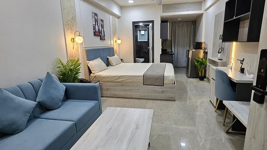 A side view of the spacious room with furniture and a table placed near the window, and a bed at the farthest end at Urban Suites by BluSalzz, Jaipur.