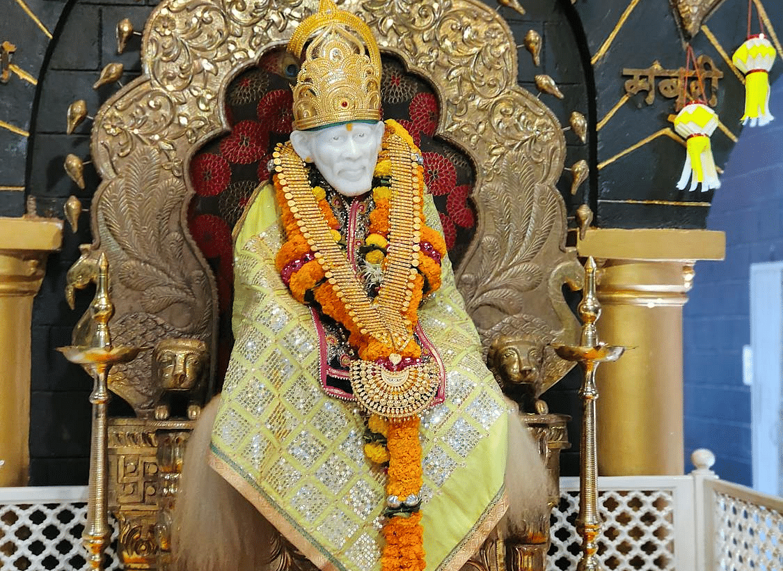 Idol of Sai baba brightly decorated with colourful clothes and garlands.