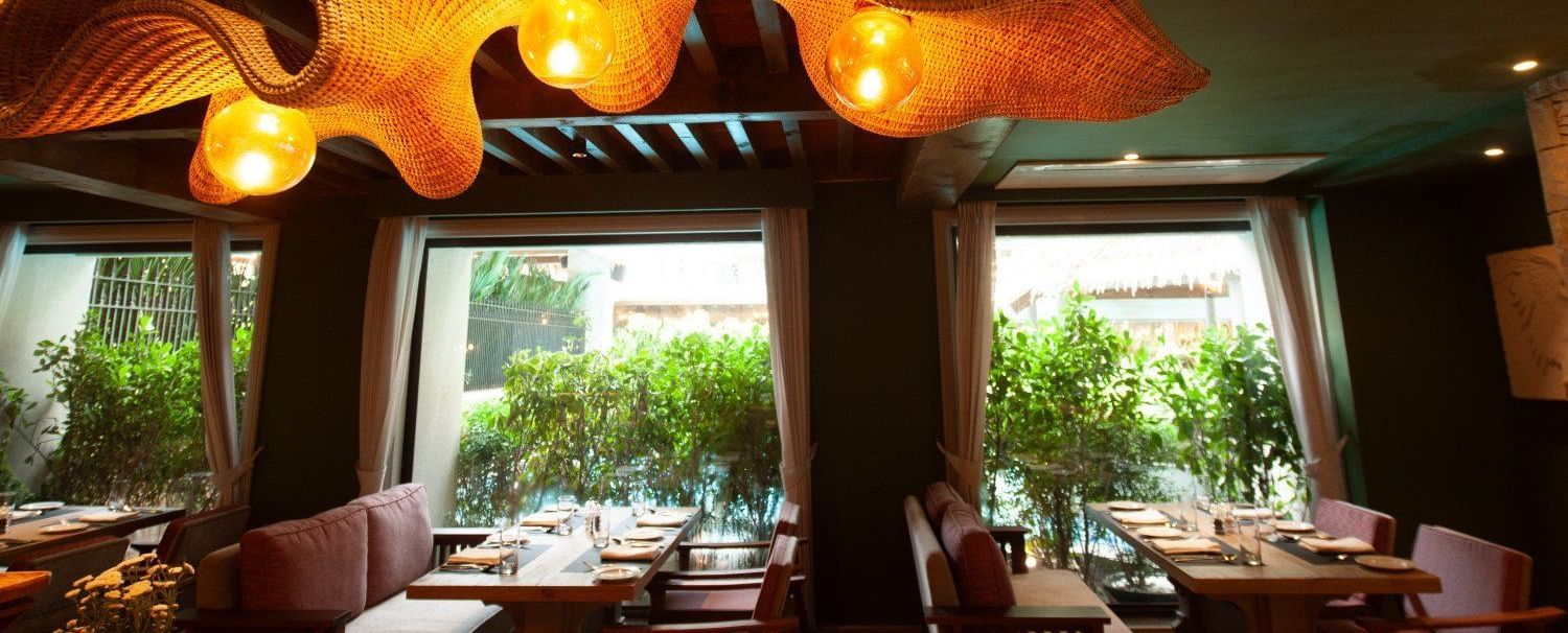 A wide-angle shot of the interior of the Mila Restaurant at The Evren, Vagator, highlighting the unique, woven light fixtures hanging from the wooden ceiling.