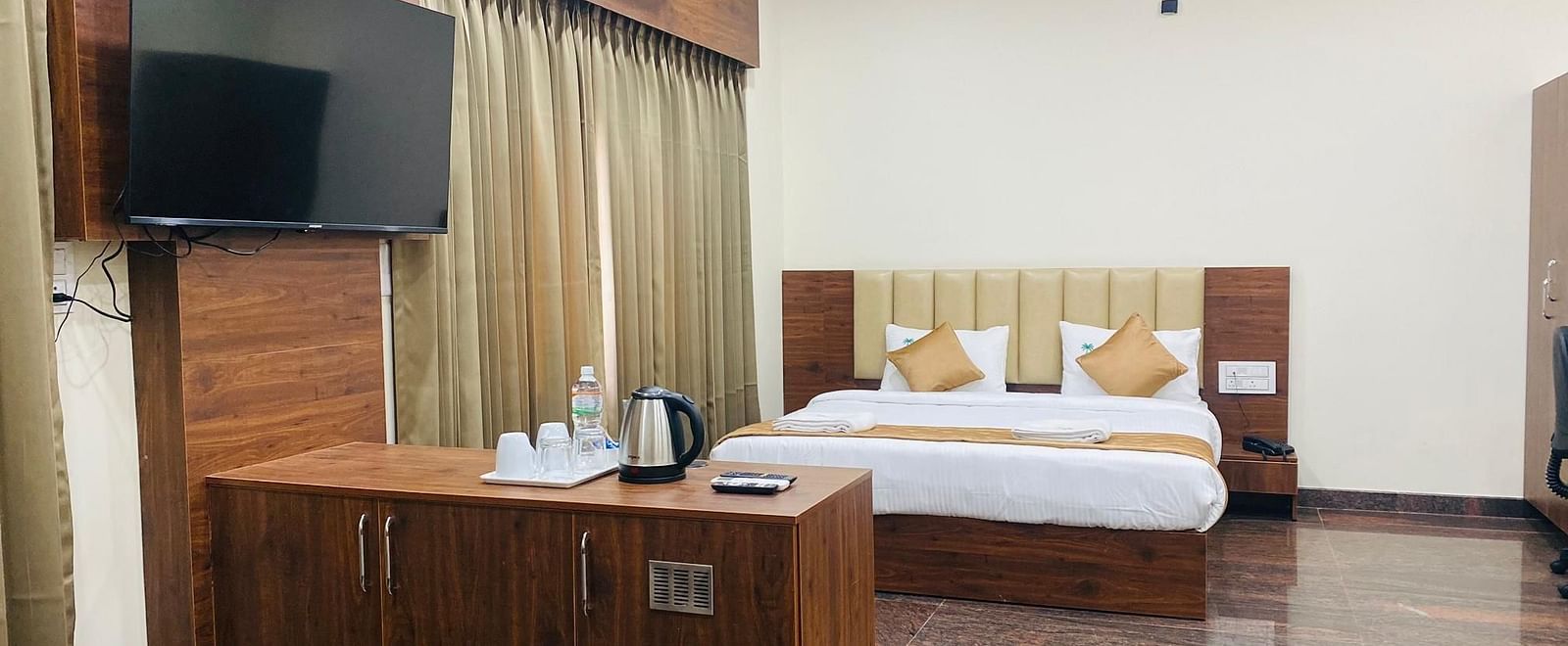 A hotel room at Hotel Sahara Tree, featuring a television, comfortable bed, and wooden desk.
