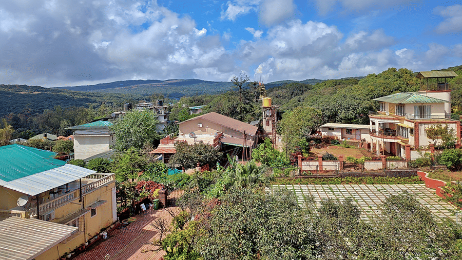 Scenic view of green hills, surrounding homes, and cloudy blue skies.