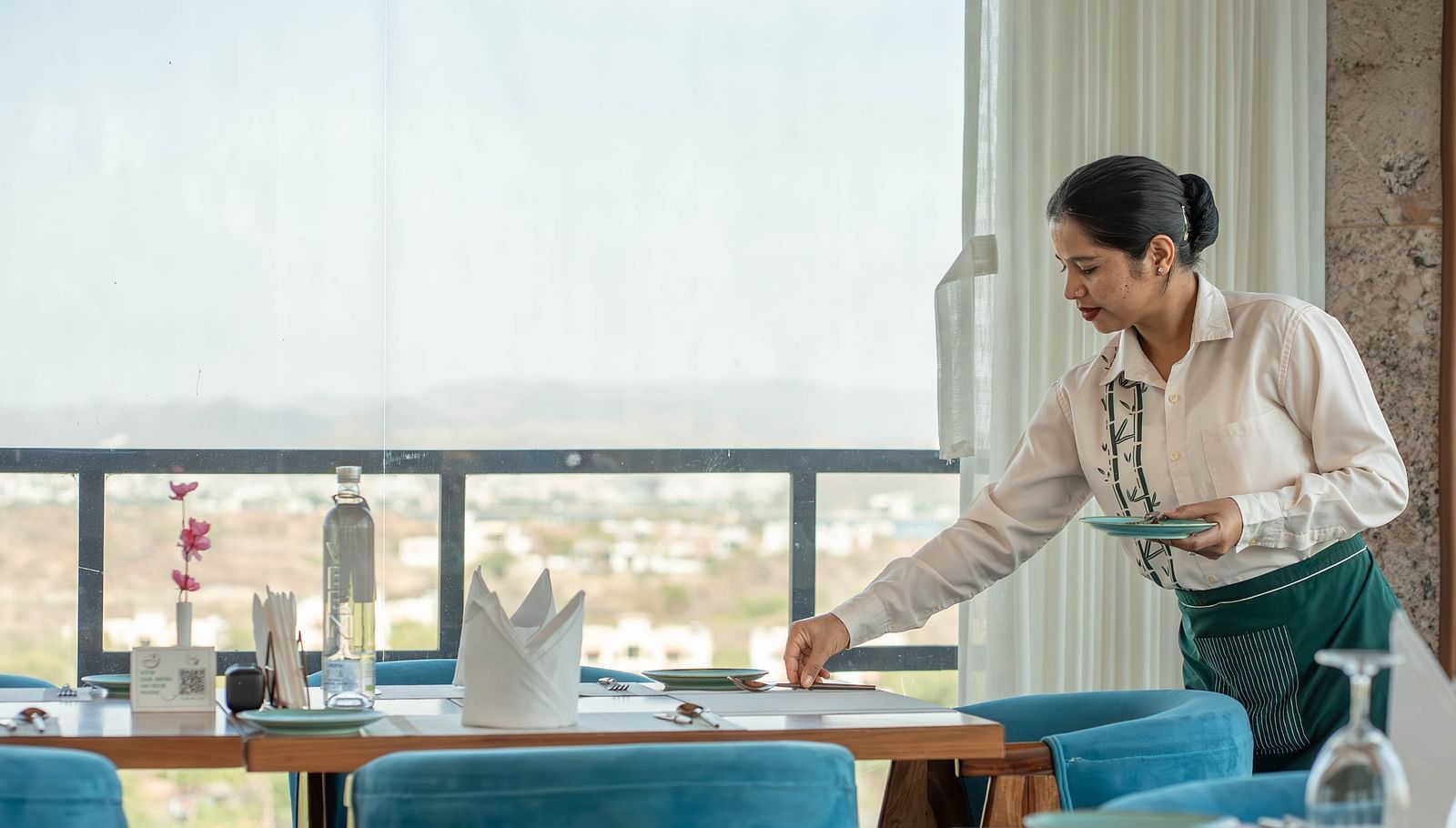 A person setting a table in a restaurant or dining area.